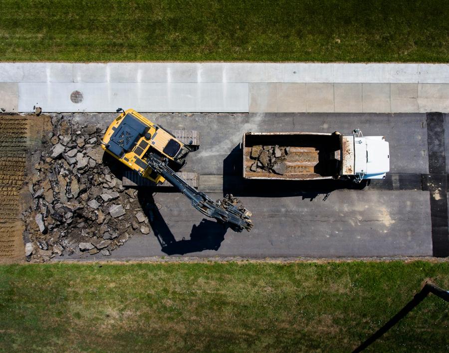 Overhead drone view of an excavator loading demolition debris into a dump truck